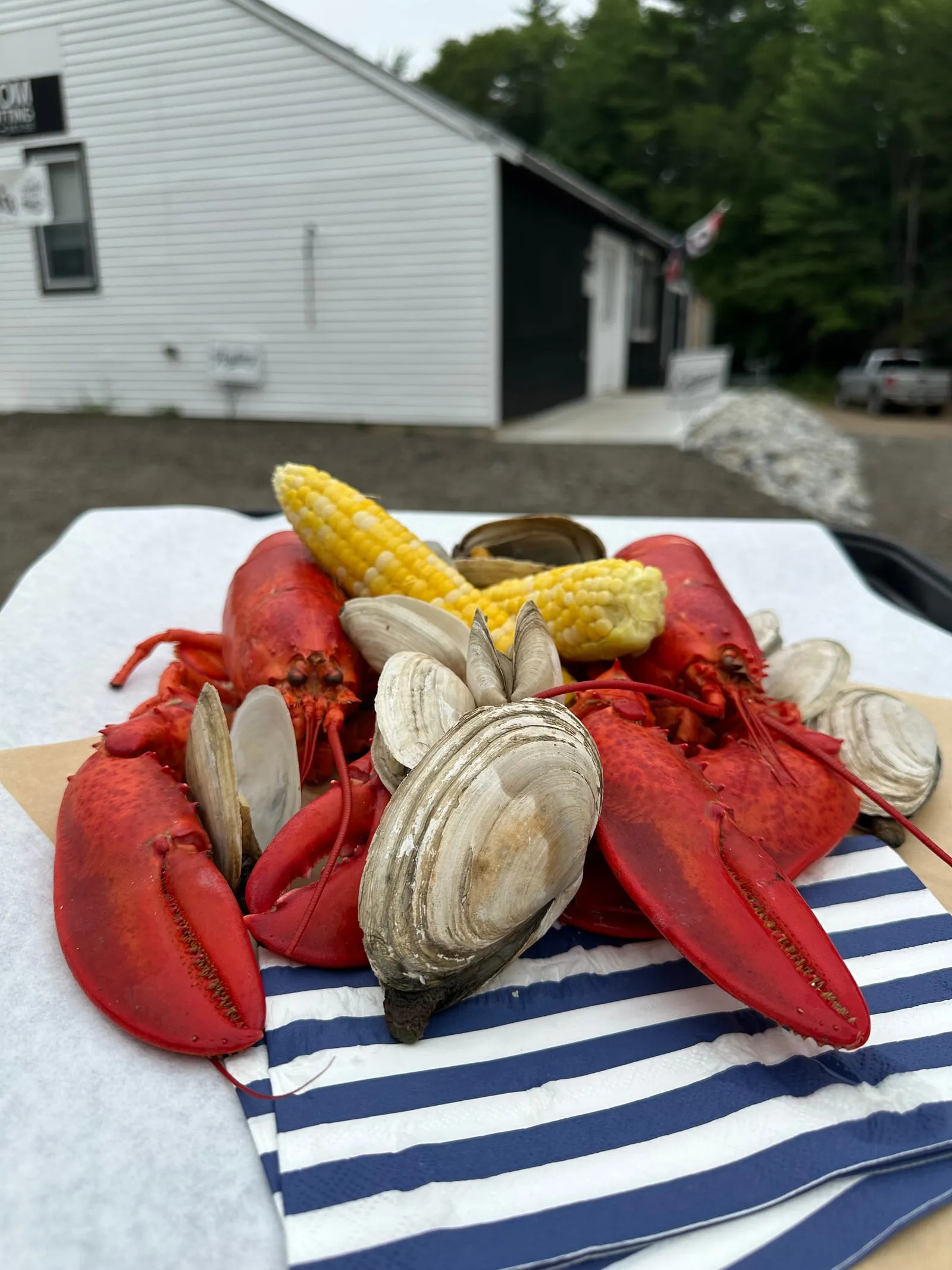 A tray of steamed Maine lobster, steamer clams and corn on the cob from Perry Butcher Co., with the shop behind